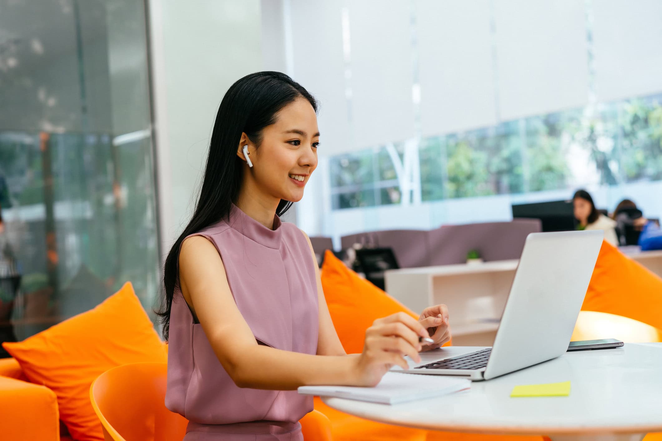 Cheerful businesswoman on video call with colleague, wearing ear phones in modern office, happiness, business startup, entrepreneur