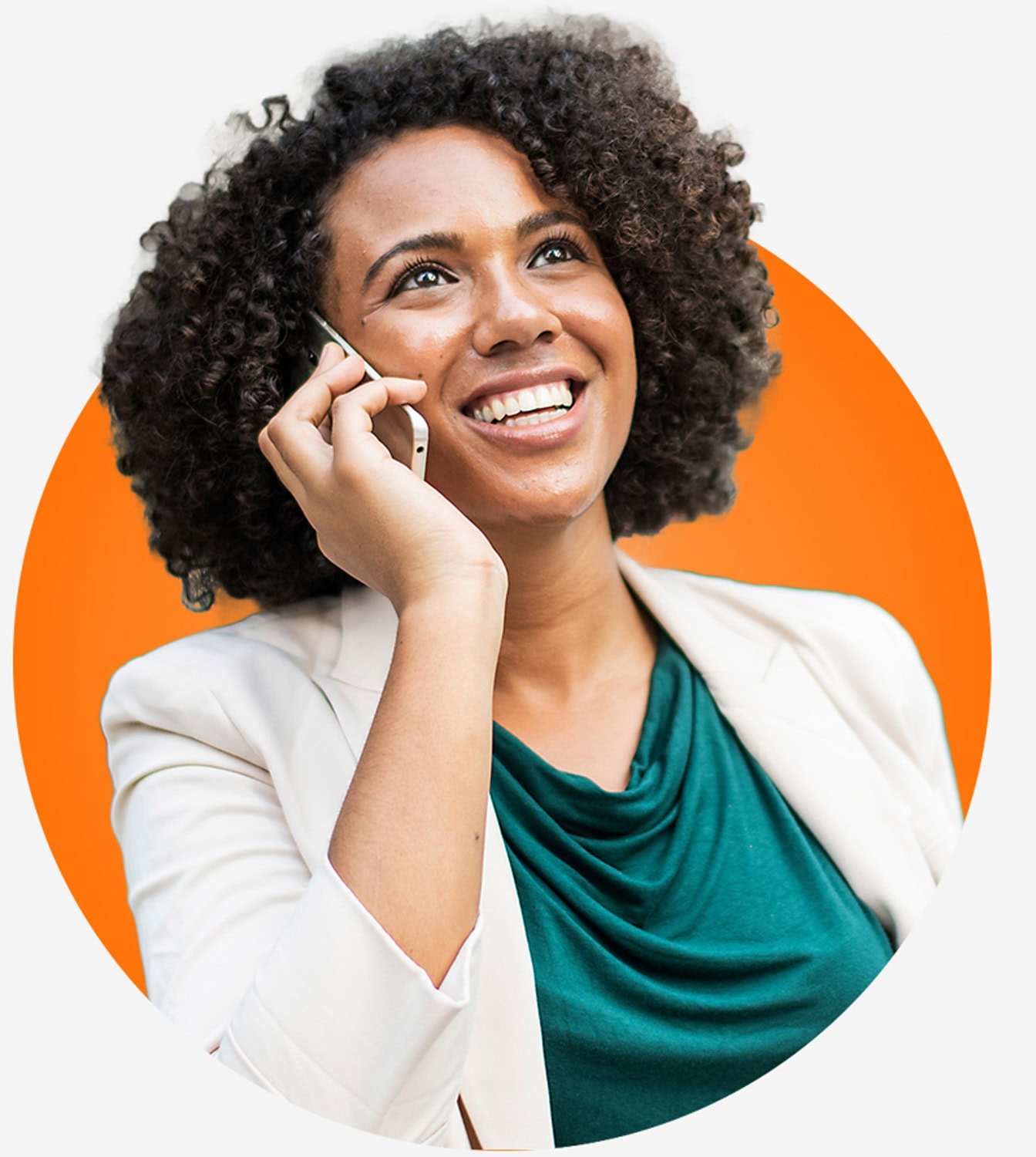 A woman with curly hair smiles while talking on a smartphone, inviting you to contact us. She wears a teal top and light-colored blazer, set against an orange circle background.