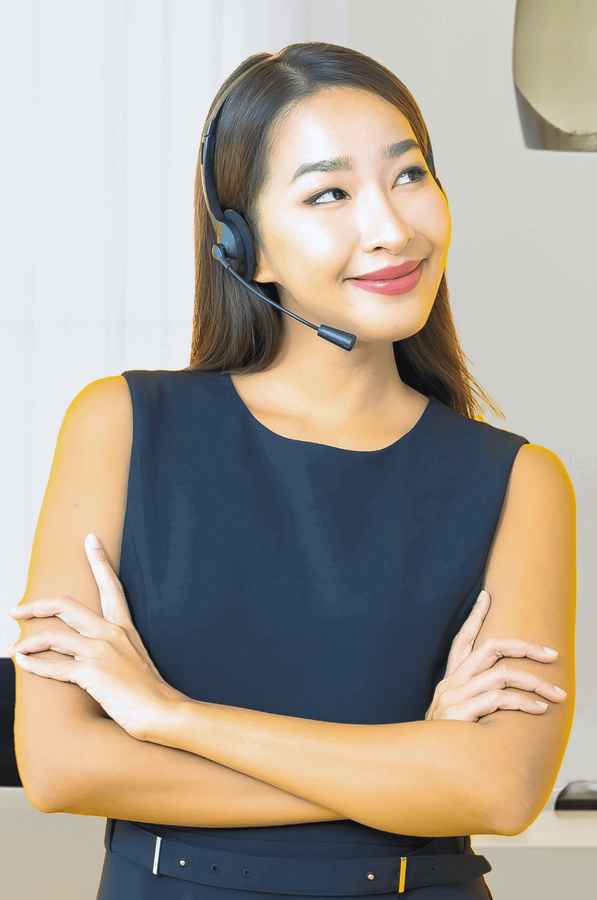 A woman wearing a black sleeveless dress and headset stands with her arms crossed, smiling slightly while looking to the side. She has long, straight hair and exudes the confidence of a loan officer assistant. The background is a softly lit indoor setting.